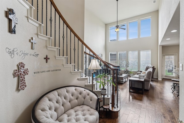 stairway with ceiling fan, wood finished floors, a towering ceiling, and baseboards