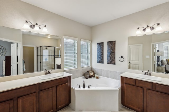 full bath featuring a bath, a stall shower, two vanities, and a sink