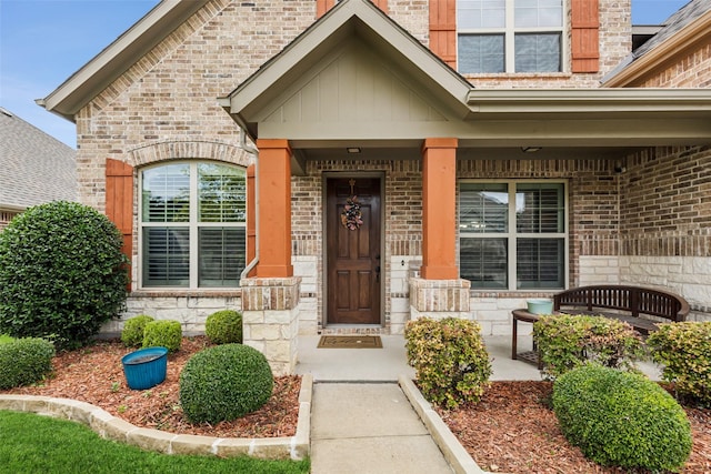 entrance to property with a porch and brick siding