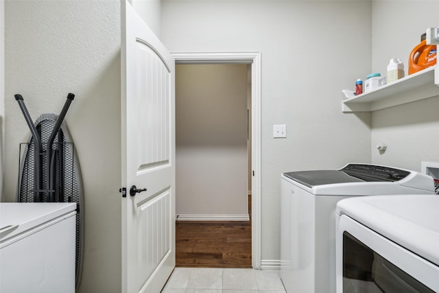 washroom with laundry area, baseboards, washer and dryer, and light tile patterned flooring