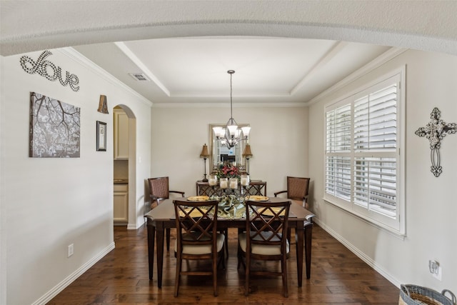 dining space with baseboards, visible vents, arched walkways, dark wood finished floors, and a tray ceiling