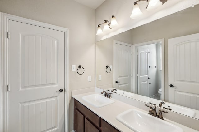 full bath with double vanity, a sink, and toilet