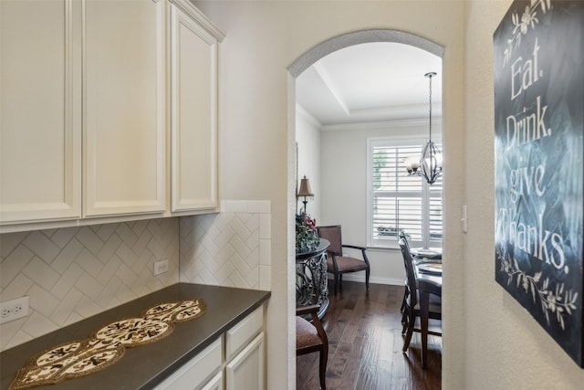 kitchen with arched walkways, dark countertops, dark wood finished floors, and white cabinetry