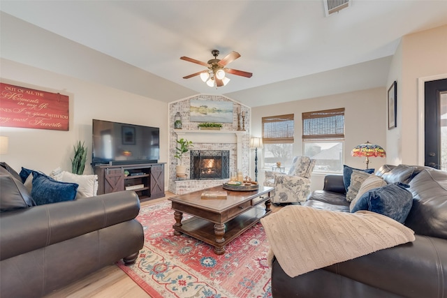 living area featuring a fireplace, visible vents, ceiling fan, lofted ceiling, and wood finished floors