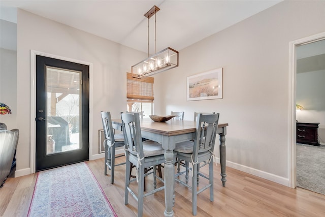 dining room with light wood-style flooring, a chandelier, and baseboards