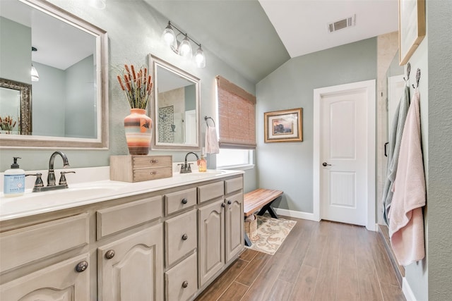 bathroom featuring wood finished floors, visible vents, a sink, and lofted ceiling