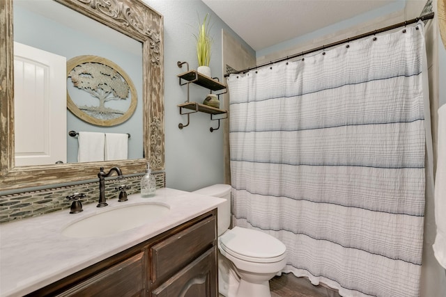 bathroom featuring toilet, vanity, and a shower with curtain