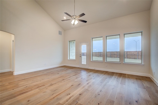 unfurnished room featuring light wood-type flooring, plenty of natural light, visible vents, and arched walkways