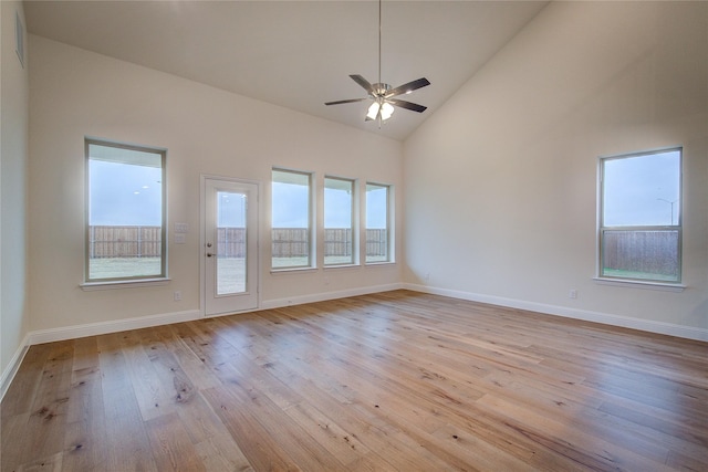 spare room with light wood-style floors, high vaulted ceiling, baseboards, and a ceiling fan