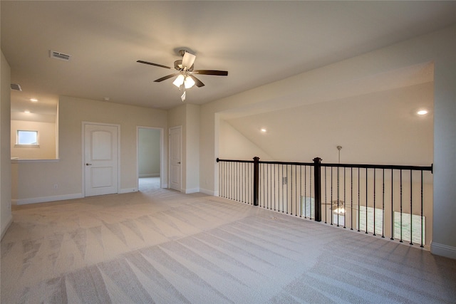 empty room featuring visible vents, baseboards, a ceiling fan, and light colored carpet