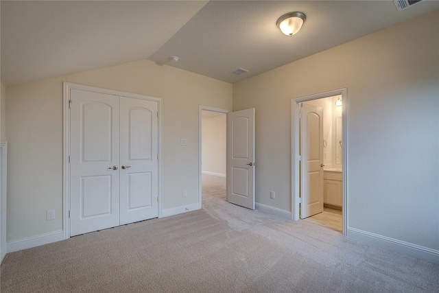 unfurnished bedroom with light carpet, baseboards, vaulted ceiling, and a closet