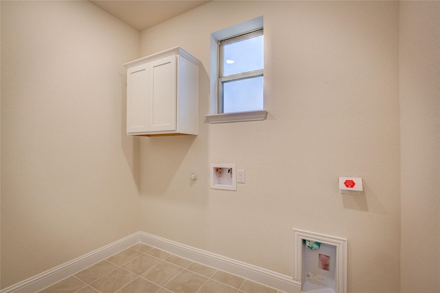 clothes washing area with cabinet space, light tile patterned floors, baseboards, hookup for a gas dryer, and hookup for a washing machine