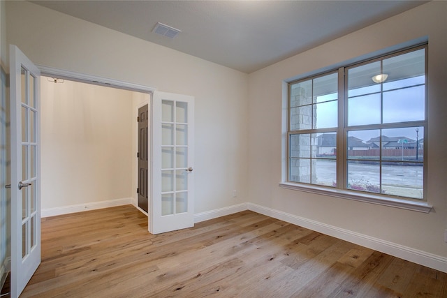 unfurnished room featuring french doors, visible vents, baseboards, and light wood finished floors