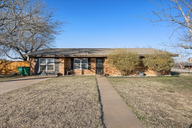 view of front of house with a front yard, brick siding, and fence