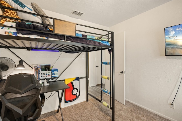 bedroom featuring carpet floors, visible vents, a textured wall, and a textured ceiling