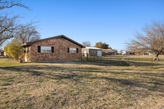 view of side of property with brick siding, a lawn, and fence