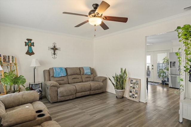 living area with ornamental molding, dark wood finished floors, visible vents, and a ceiling fan