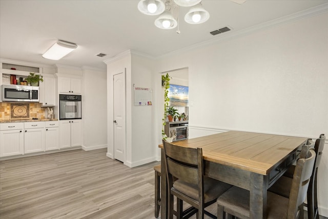 dining area featuring light wood-style floors, visible vents, and crown molding