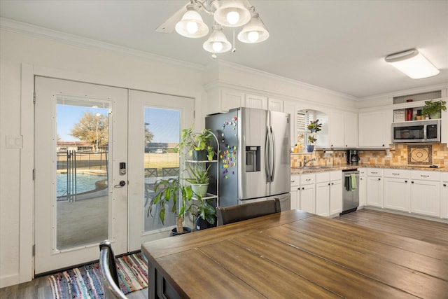 kitchen with stainless steel appliances, a sink, white cabinets, hanging light fixtures, and open shelves