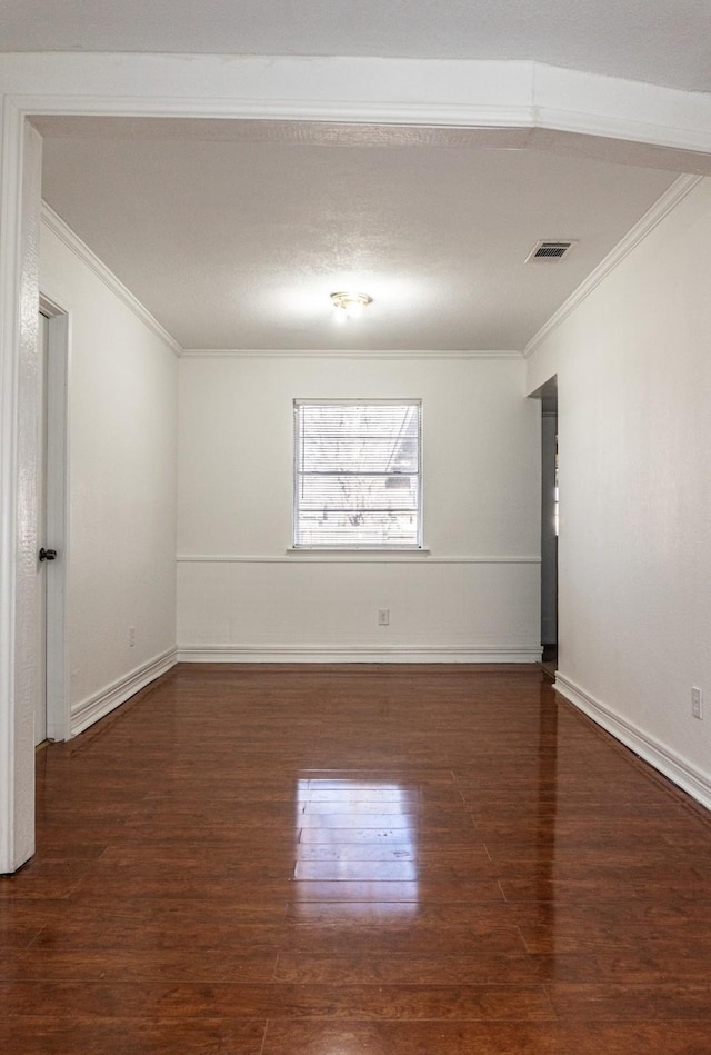 spare room featuring baseboards, visible vents, ornamental molding, and dark wood-type flooring