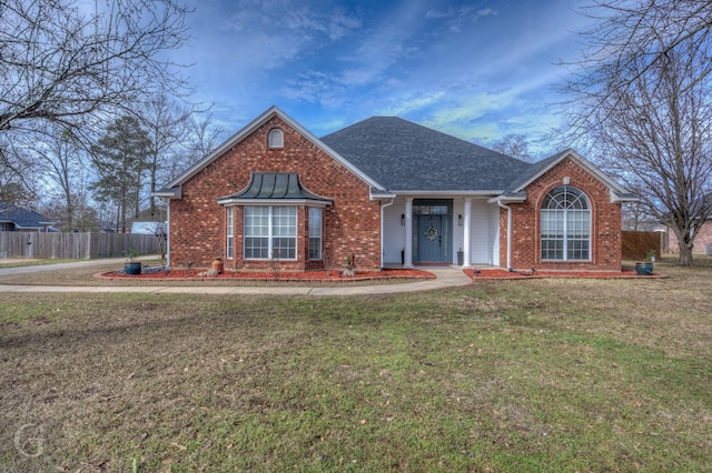 view of front of property featuring a front yard, brick siding, fence, and roof with shingles