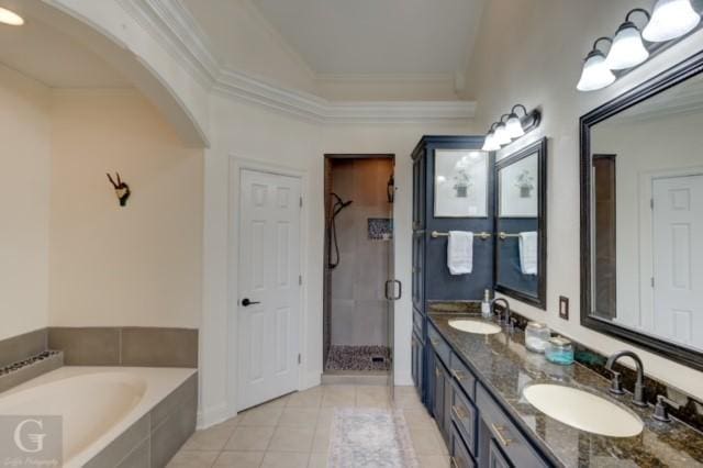 bathroom with crown molding, a garden tub, a sink, and tile patterned floors