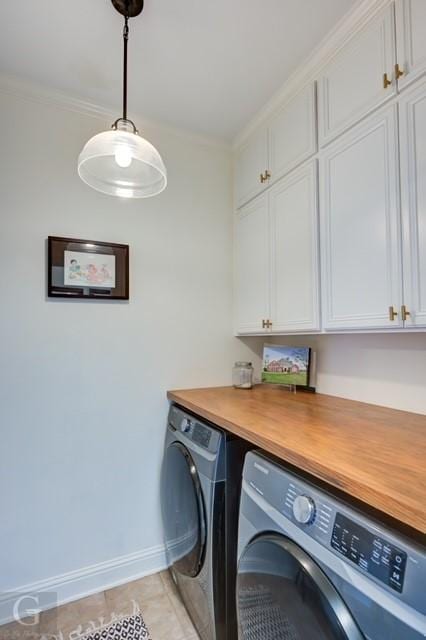 laundry area featuring light tile patterned flooring, washing machine and dryer, baseboards, ornamental molding, and cabinet space