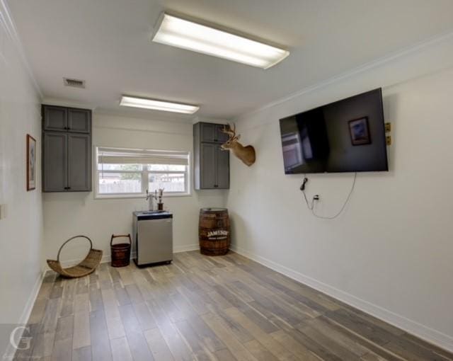 interior space featuring freestanding refrigerator, light wood finished floors, visible vents, and baseboards