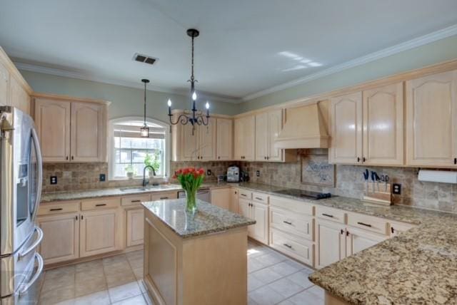 kitchen featuring visible vents, stainless steel fridge with ice dispenser, custom range hood, a kitchen island, and light stone countertops