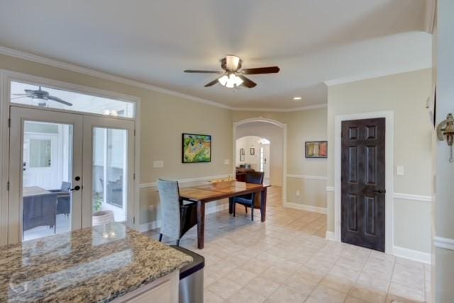 dining space featuring baseboards, ceiling fan, arched walkways, and crown molding