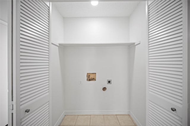 washroom featuring a textured ceiling, light tile patterned flooring, hookup for an electric dryer, laundry area, and washer hookup