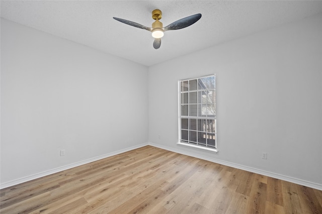 empty room featuring light wood-style floors, ceiling fan, baseboards, and a textured ceiling