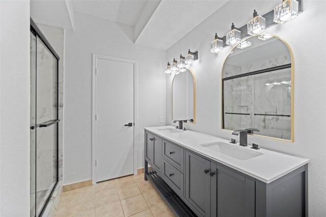 bathroom featuring double vanity, a marble finish shower, a sink, and tile patterned floors