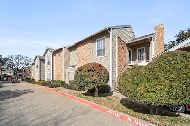 view of home's exterior featuring a residential view, a chimney, and brick siding