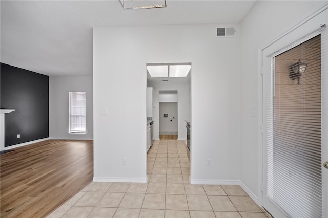 interior space featuring light tile patterned floors, visible vents, and baseboards