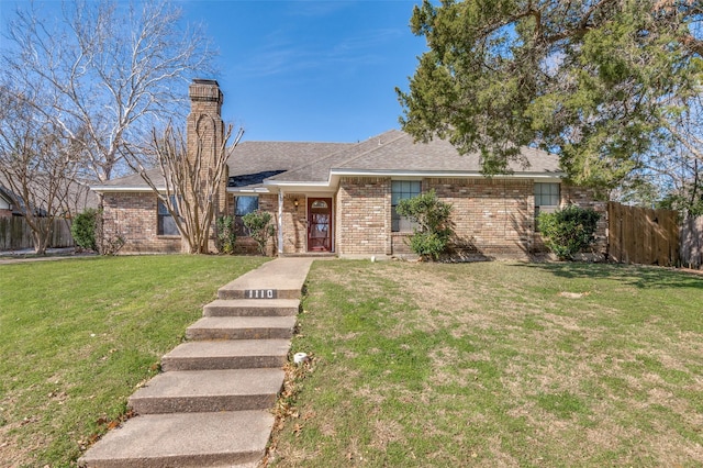 ranch-style home with brick siding, fence, roof with shingles, a front lawn, and a chimney