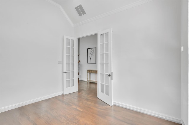 spare room with french doors, crown molding, visible vents, vaulted ceiling, and wood finished floors