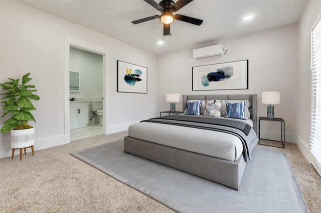 bedroom with baseboards, carpet, ensuite bathroom, and a wall unit AC