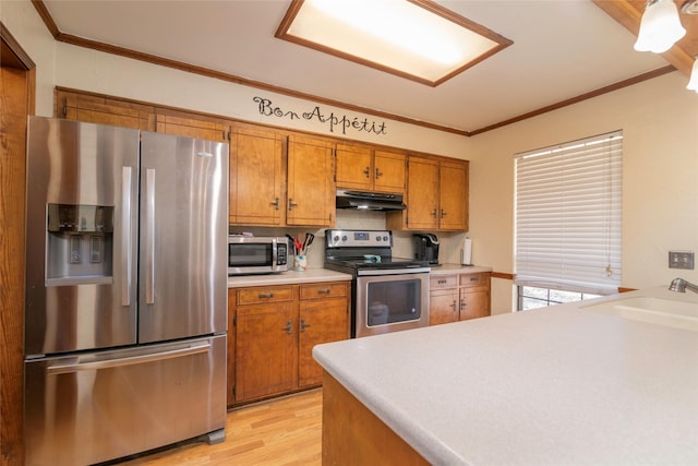 kitchen featuring light countertops, appliances with stainless steel finishes, ornamental molding, a sink, and under cabinet range hood