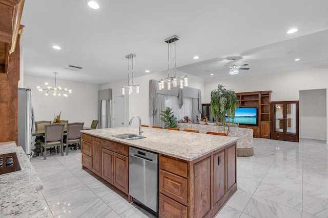 kitchen with light stone countertops, appliances with stainless steel finishes, a sink, and decorative light fixtures