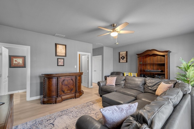 living room featuring light wood finished floors, baseboards, visible vents, and a ceiling fan