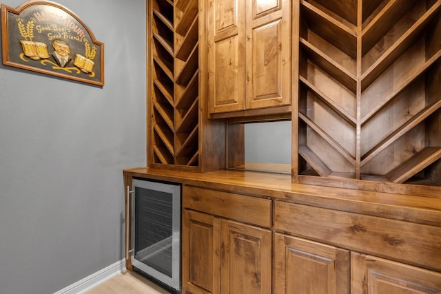 wine cellar with a bar, beverage cooler, and baseboards