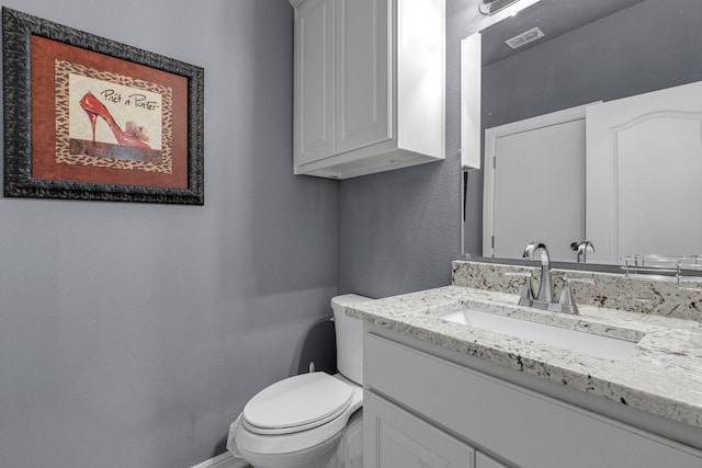 bathroom with toilet, baseboards, visible vents, and vanity