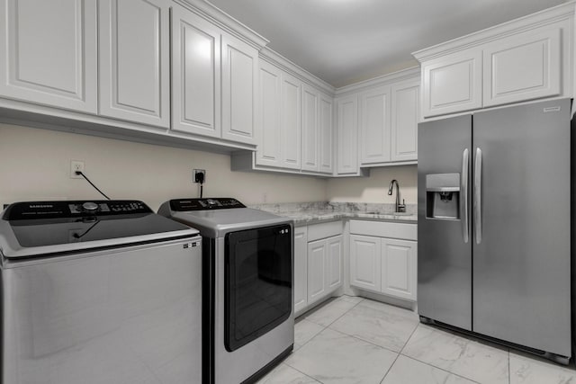 washroom featuring marble finish floor, cabinet space, washer and clothes dryer, and a sink