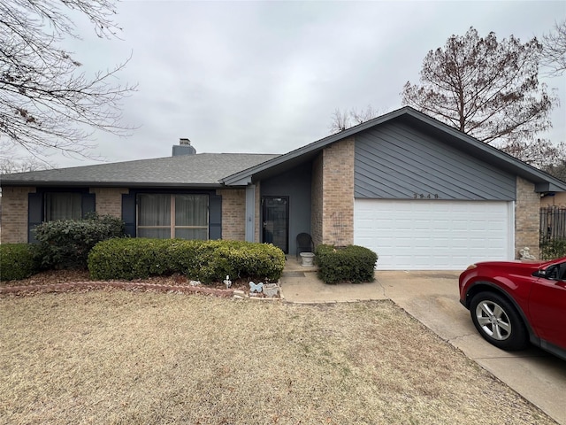 view of front of property with brick siding, driveway, a chimney, and an attached garage