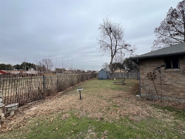 view of yard featuring an outbuilding, a fenced backyard, and a storage shed