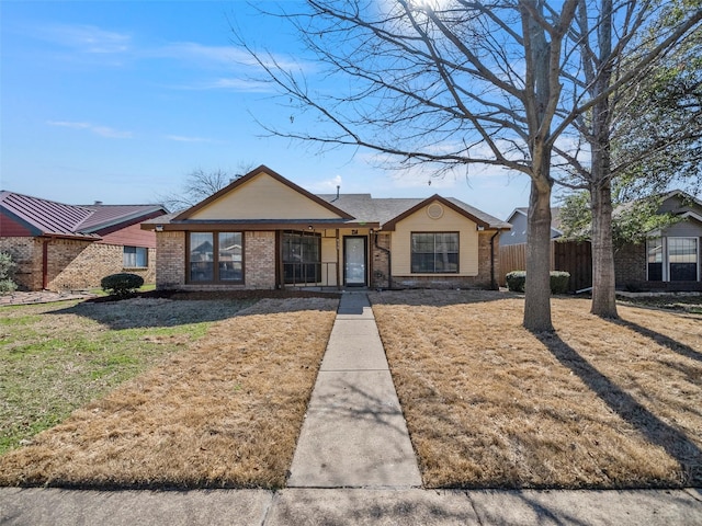 view of front of house featuring fence, a front lawn, and brick siding