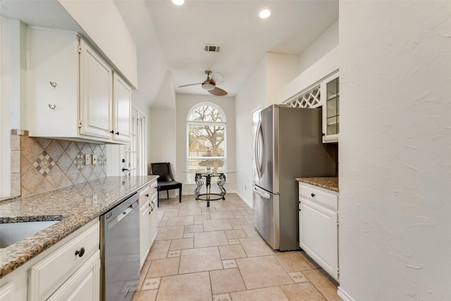9005 Cumberland Dr, Irving, TX 75063 - kitchen with appliances with stainless steel finishes, tasteful backsplash, light stone counters, a ceiling fan, and glass insert cabinets