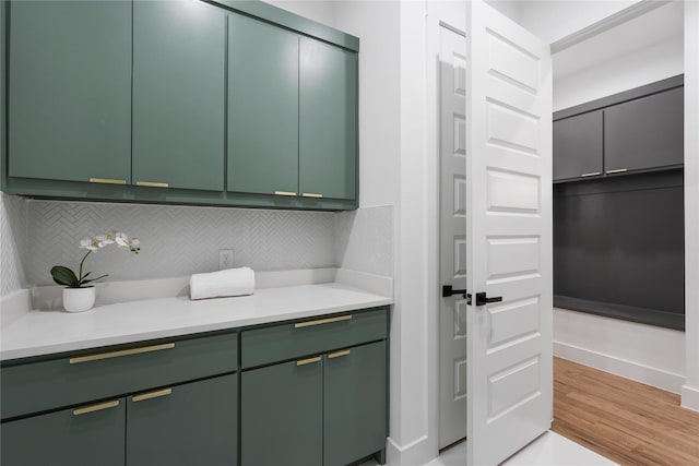 kitchen with light wood-style floors, decorative backsplash, light countertops, and green cabinetry