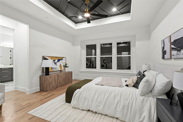 bedroom featuring light wood-type flooring, ceiling fan, ensuite bath, and baseboards